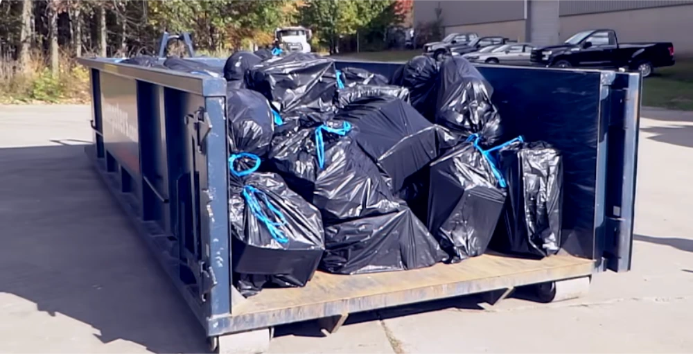 Household trash bags being loaded into a rental dumpster in Lawton, OK
