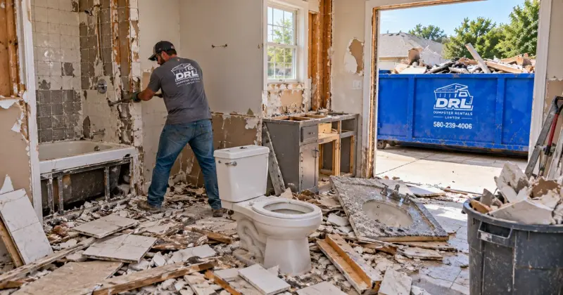 Bathroom demolition waste including tile, drywall, wood, fixtures, and debris being cleared for dumpster disposal in Lawton, Oklahoma