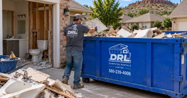 Bathroom renovation debris including tile, drywall, wood, and fixtures being loaded into a 15-yard dumpster in Lawton, Oklahoma