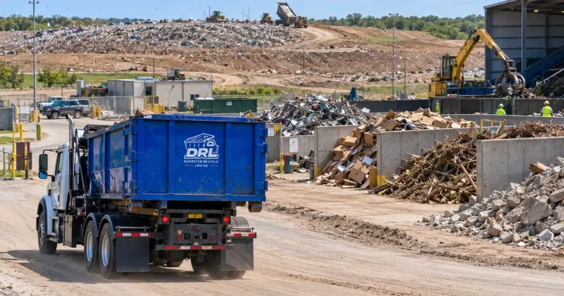 Roll-off dumpster arriving at a landfill and recycling facility after waste pickup, with debris sorting and disposal operations