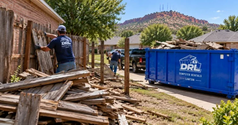 Fence removal debris including wooden fence panels, posts, and broken lumber being loaded into a roll-off dumpster in Lawton, Oklahoma