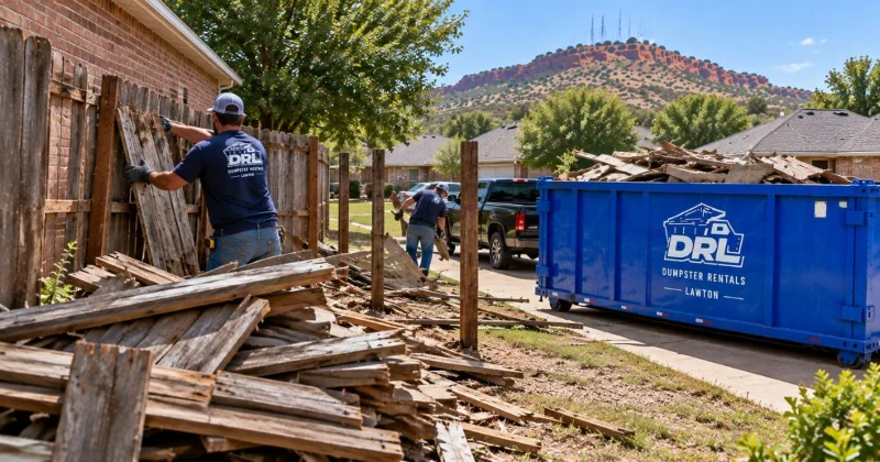 Fence removal debris including wooden fence panels, posts, and broken lumber being loaded into a roll-off dumpster in Lawton, Oklahoma