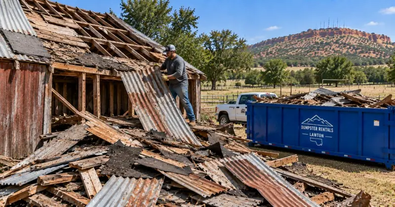 Old barn roofing materials including corrugated metal panels, shingles, wood sheathing, and roofing debris during demolition in Lawton, Oklahoma