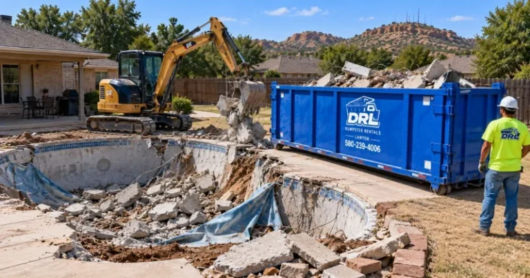 Pool removal debris including broken concrete, pool liner, rebar, and rubble being loaded into a dumpster in Lawton, Oklahoma