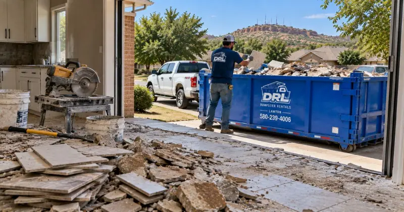 Tile and stone flooring removal debris including broken tiles, rubble, and renovation waste beside a dumpster in Lawton, Oklahoma