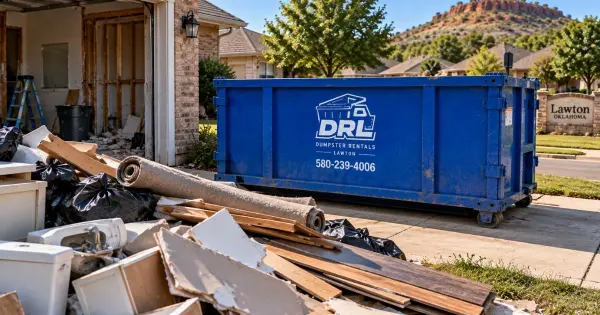 Home renovation debris including flooring, drywall, cabinets, fixtures, and lumber beside a roll-off dumpster in a Lawton, Oklahoma neighborhood